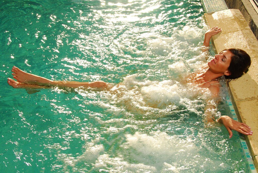 Person floating in a clear pool at Alma del Lago Suites