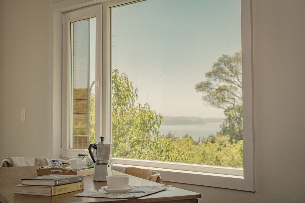 Table with books and coffee maker beside a window with trees
