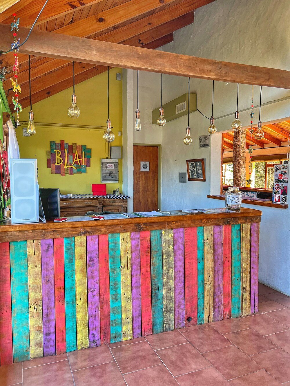 Barra de madera colorida con techo rústico y lámparas colgantes