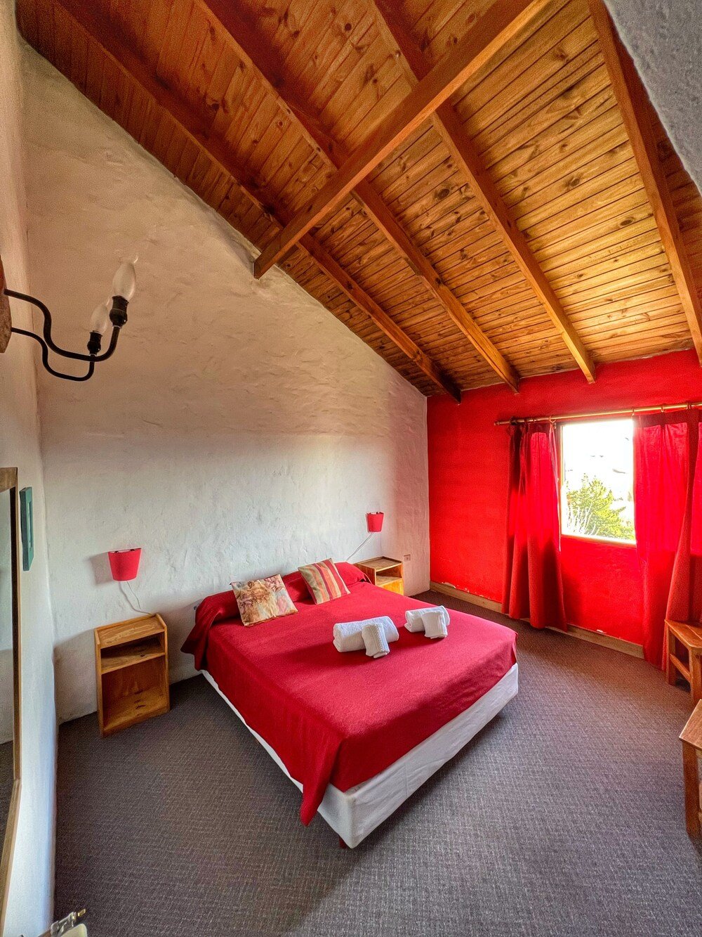 Dormitorio con techo de madera y cubrecama rojo