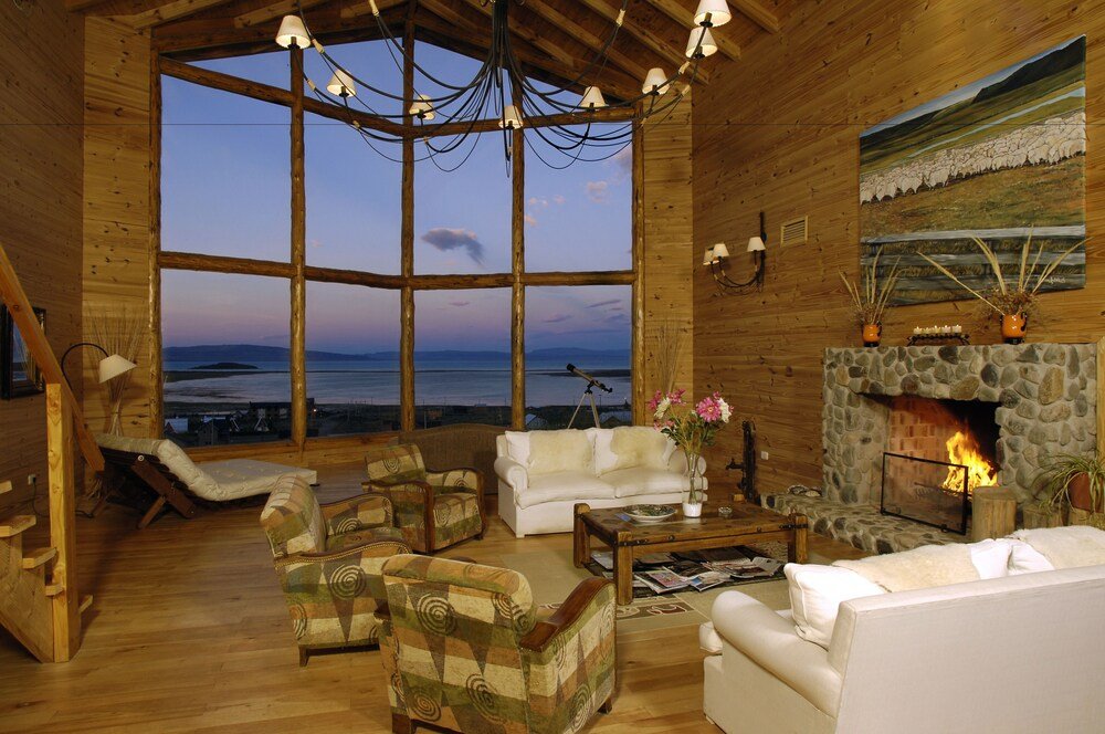 Log cabin interior with a stone fireplace and large windows