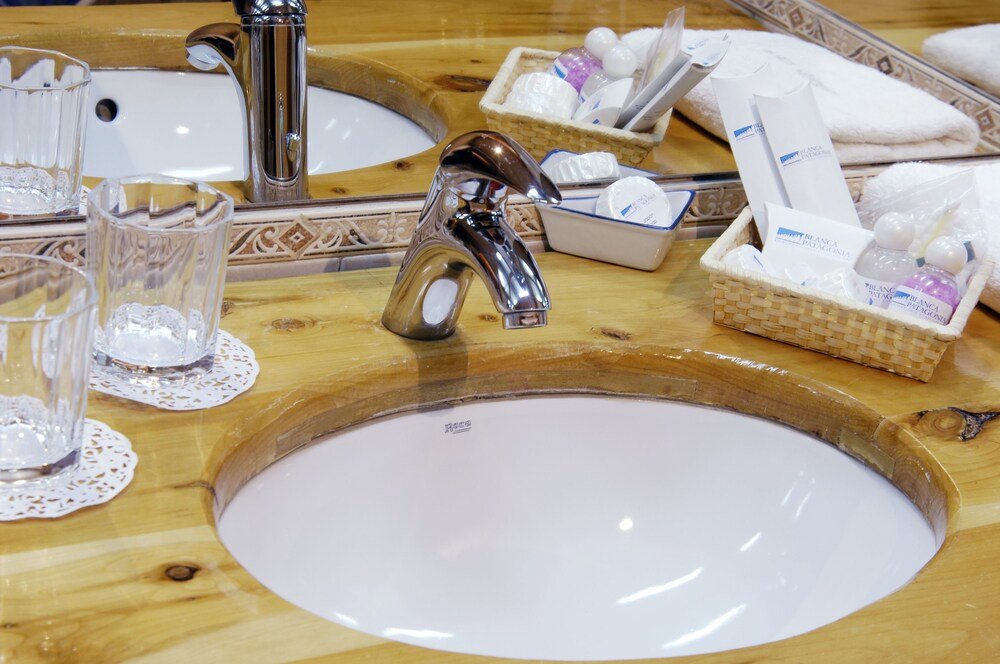 Lavatorio de baño con grifería cromada y un vaso de agua