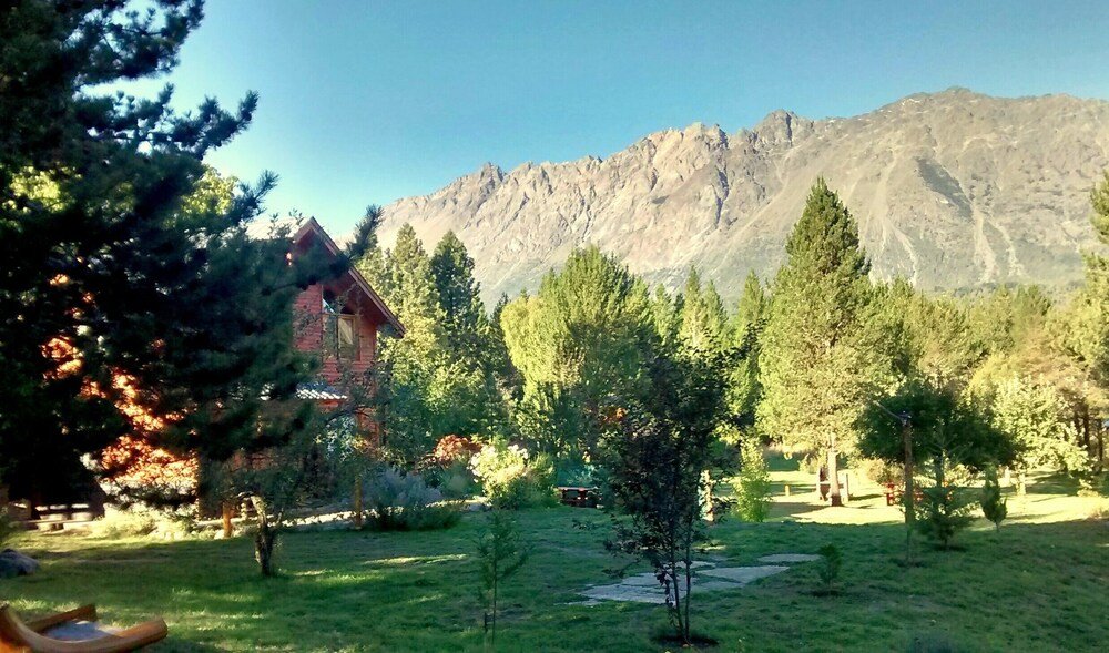 Rustic cabin surrounded by forest with a mountain backdrop