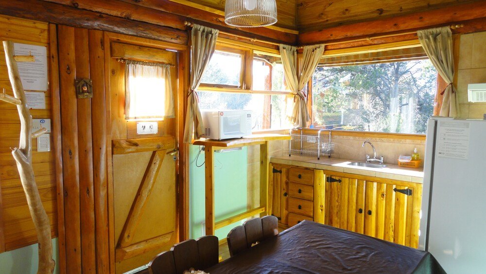 Wooden cabin interior with a dining table, chairs and a kitchenette