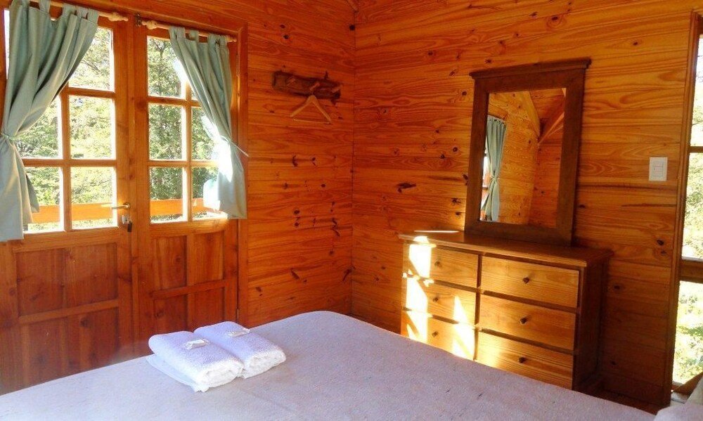 Wooden cabin room with a bed, a dresser and a mirror