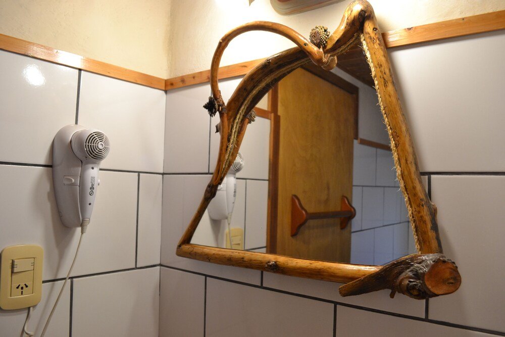Bathroom with a wooden-framed mirror, a hairdryer and a wooden door