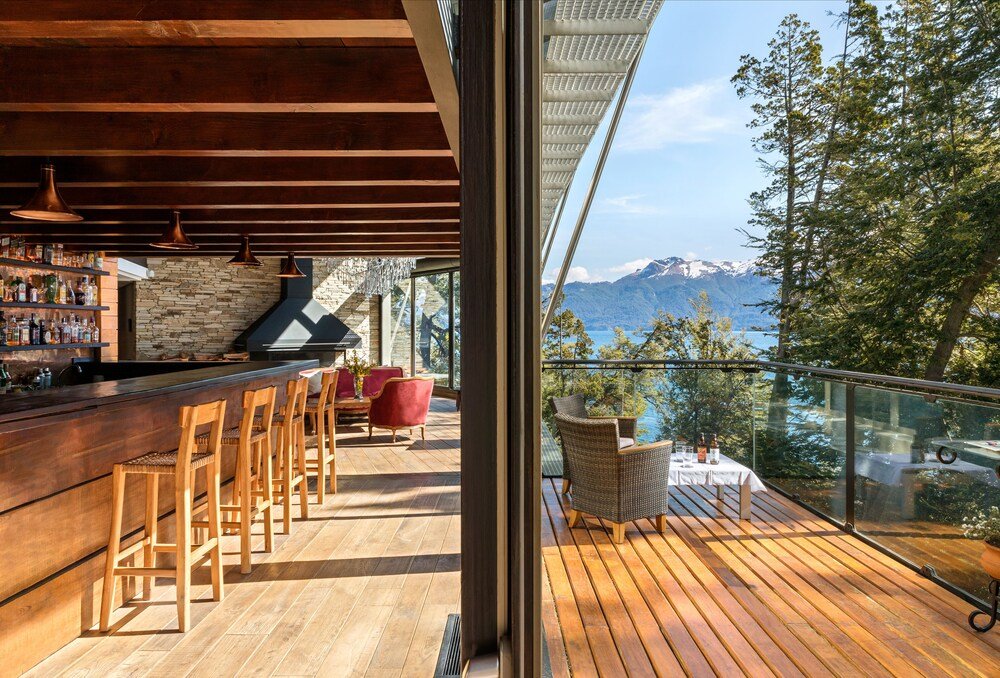 Deck de madera con barra, sillones de mimbre y vista