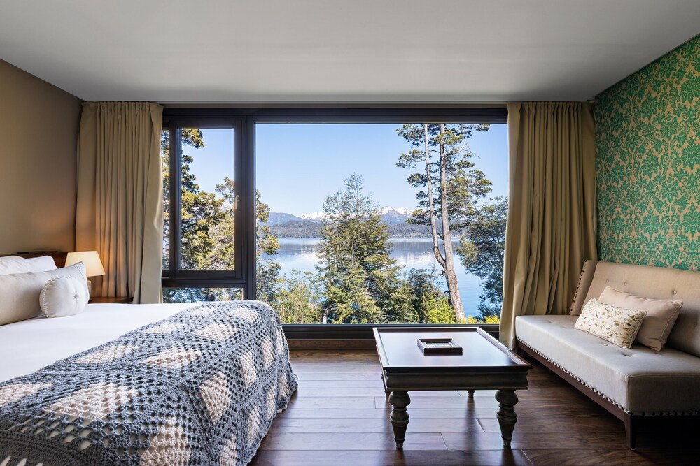 Dormitorio con gran ventana, cama, sofá y mesa ratona