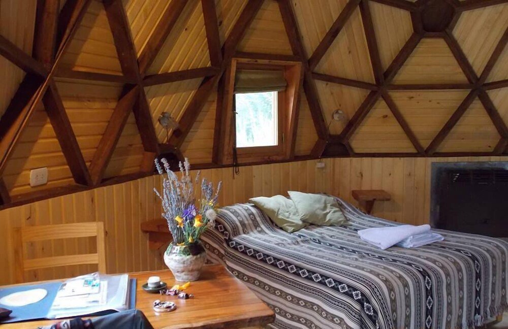 Cozy room with a wooden ceiling, patterned bedding and a view of trees