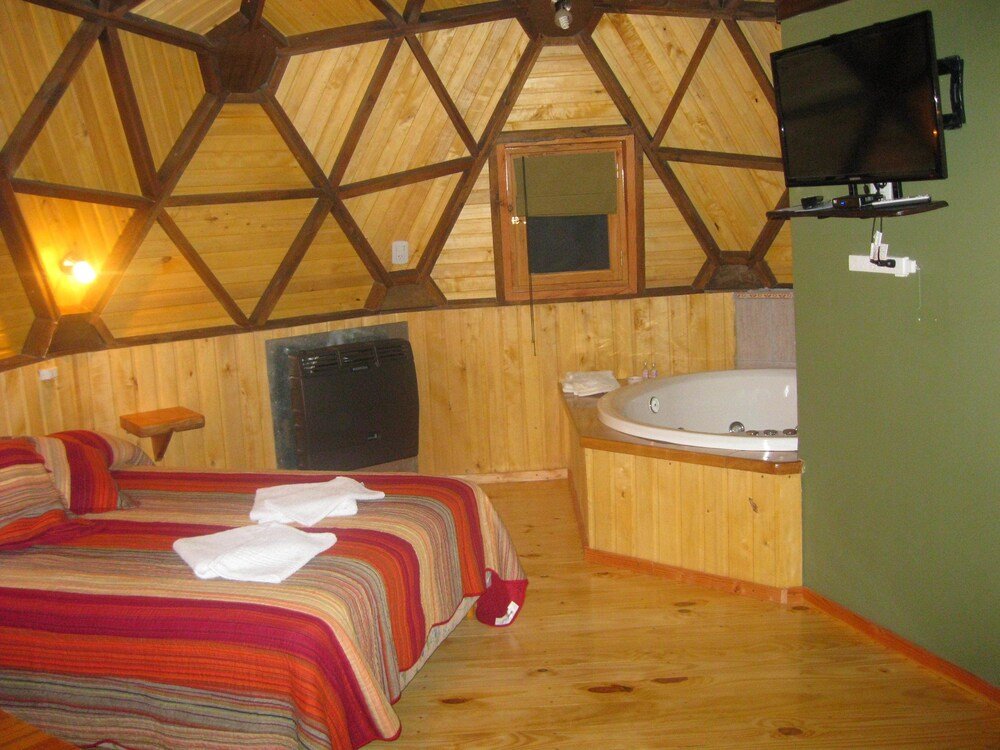 Cozy room with a bed, a large window, a television and a bathtub