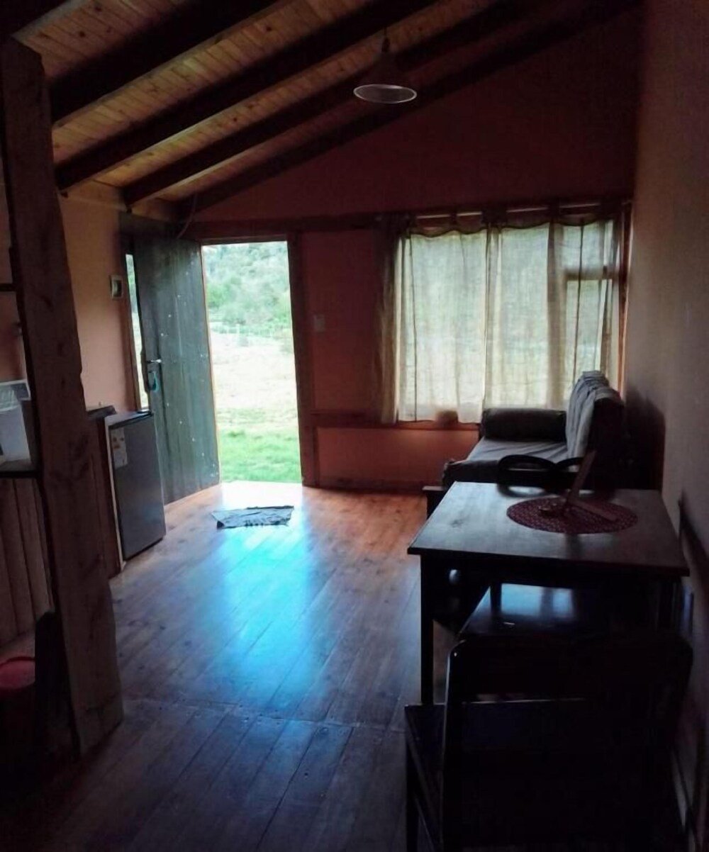 Ambiente con techo de madera, mesa con sillas y ventana
