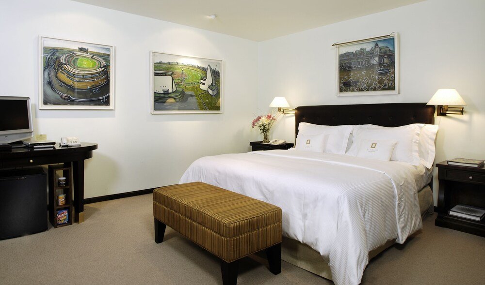 Habitación de hotel con una cama, un escritorio y dos cuadros