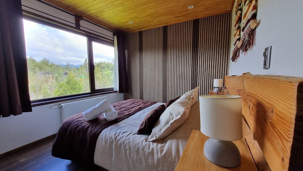 Bedroom with wooden headboard, curtains and beige bedspread