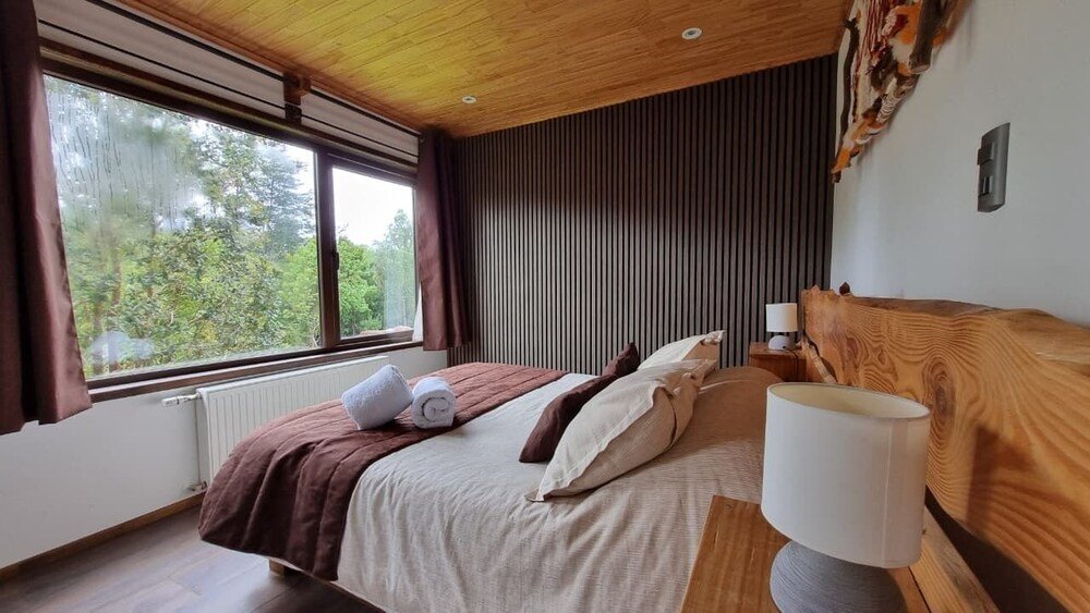 Twin bedroom with wooden beams and window onto the trees