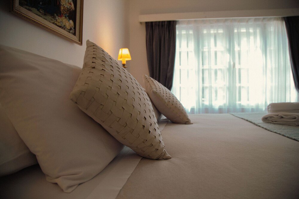 Cama bien tendida con dos almohadones estampados en una habitación