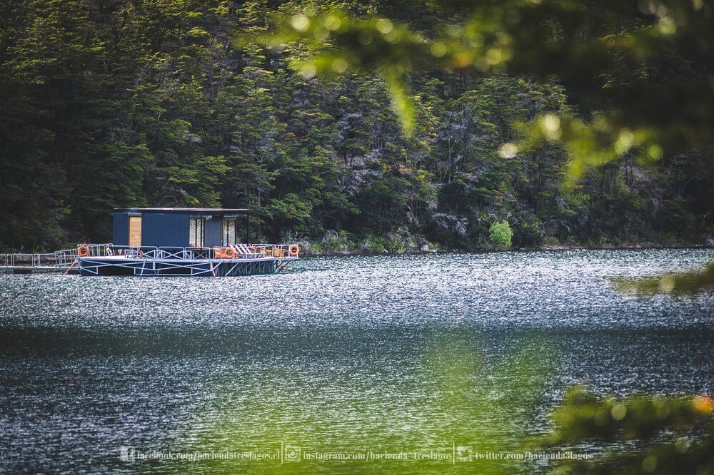 Casa flotante en un lago tranquilo rodeado de bosque denso