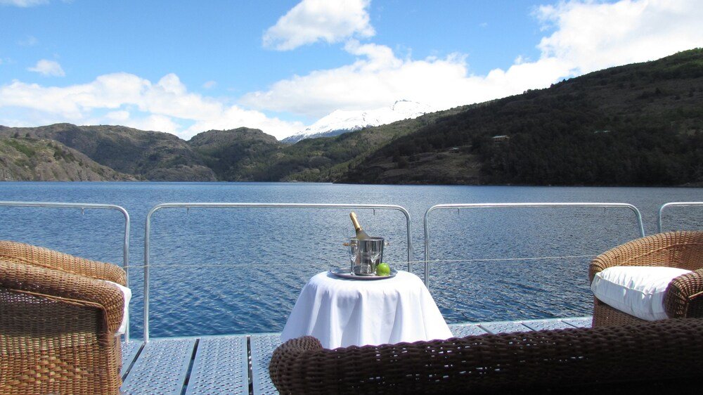 Mesa con botella y copas en la cubierta de un bote sobre el lago