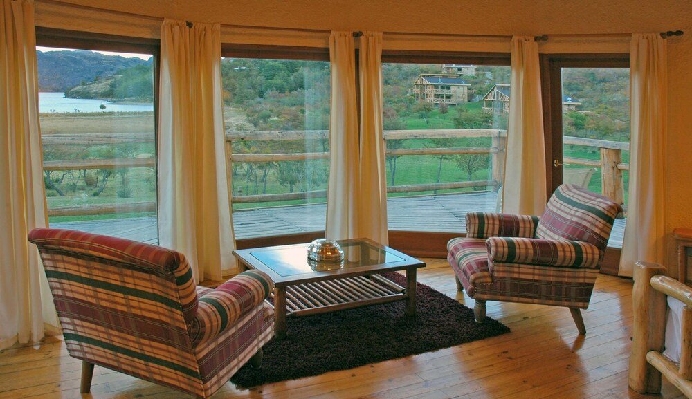Habitación con dos sillones a rayas, mesa pequeña y vista al lago