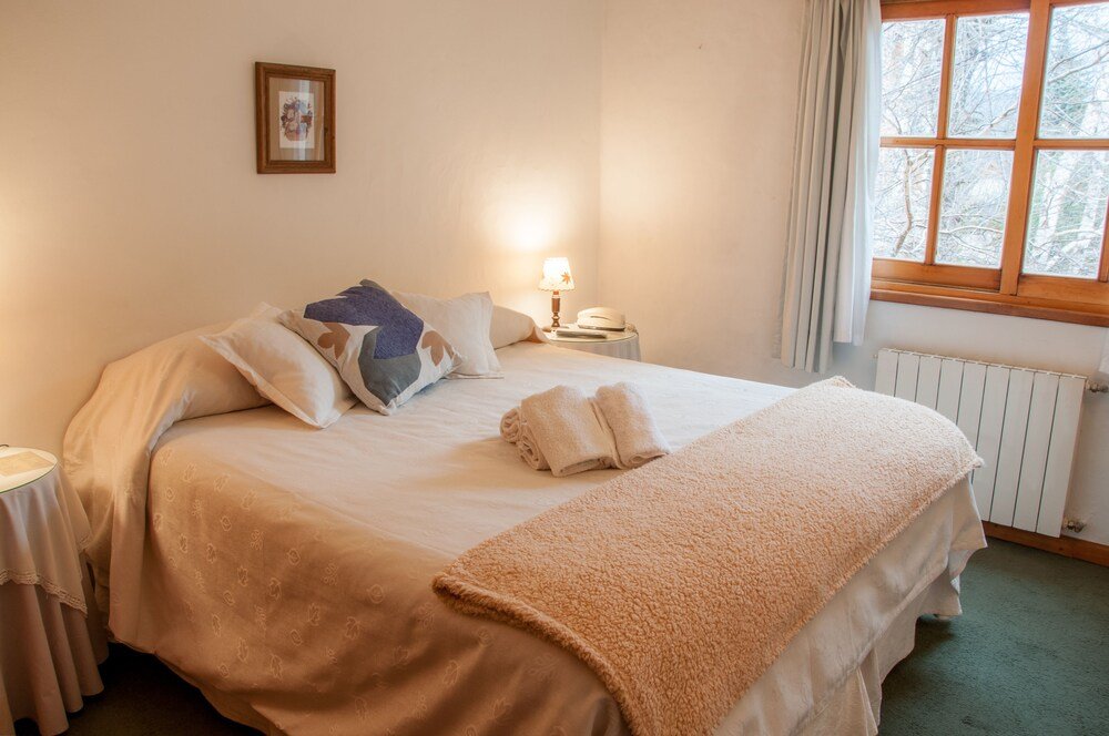 Neatly made bed with a fluffy blanket and bedside lamp