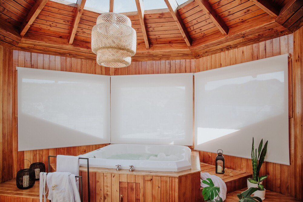 Sala de spa de madera con una bañera grande y una lámpara colgante
