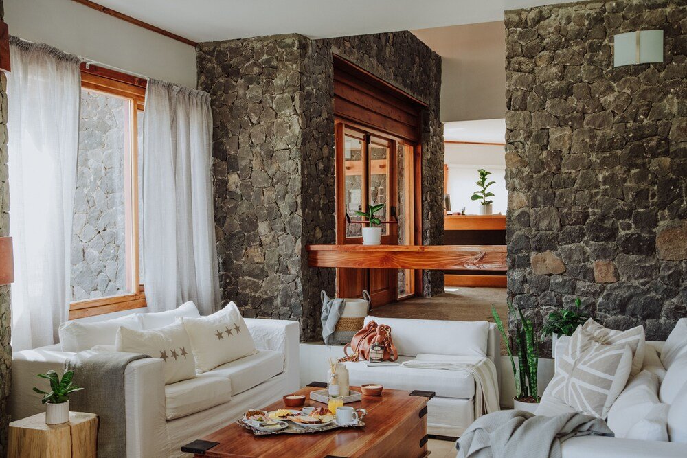 Amplio living con pared de piedra y muebles blancos