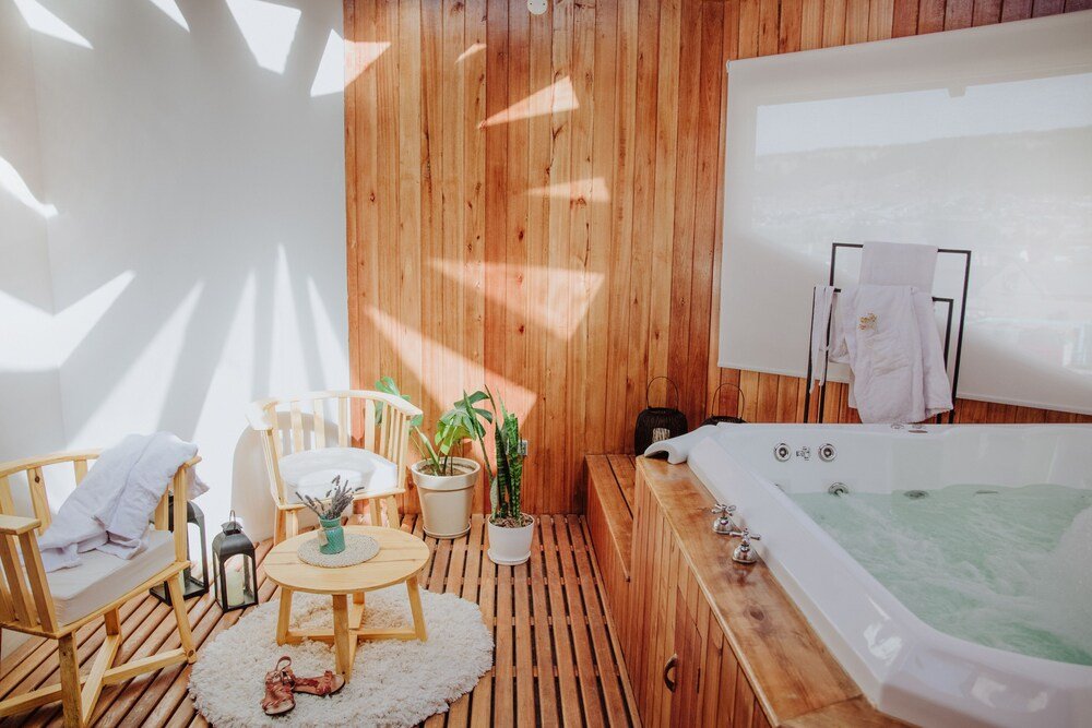 Ambiente revestido en madera con bañera y mesa pequeña con sillas