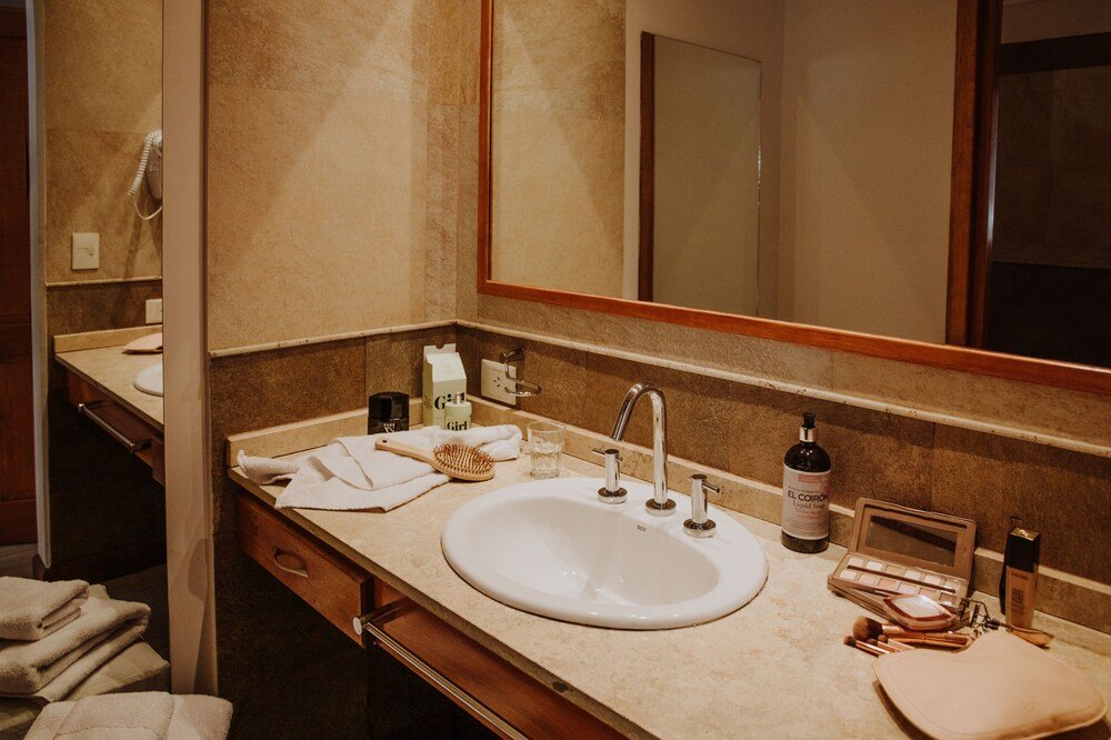 Baño con espejo grande, lavabo y artículos de tocador