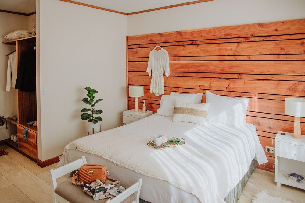 Dormitorio con respaldo de madera y ropa de cama blanca