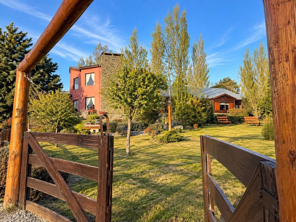 Wooden gate leading to a grassy area with a red building