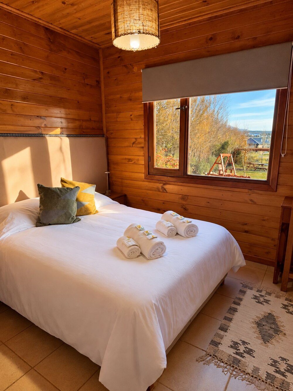 Wooden room with a bed, pillows and a window