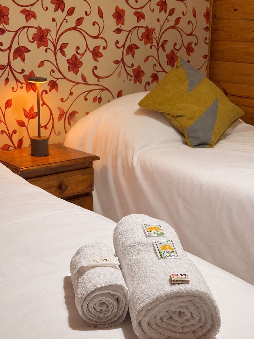 Neatly made bed with white bedding and a wooden nightstand
