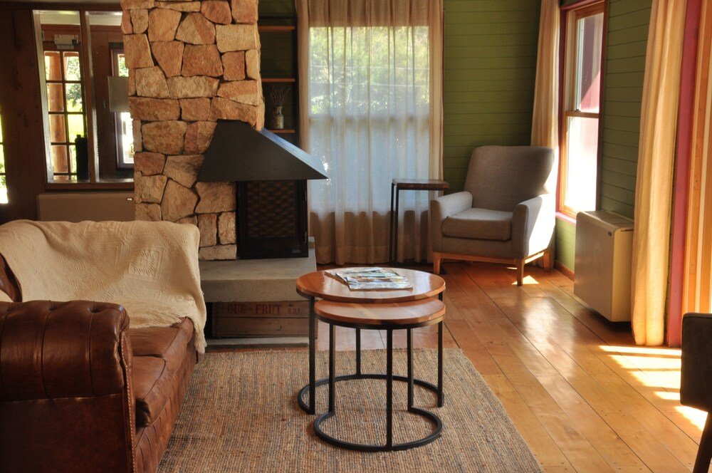 Living room with a stone fireplace, a leather sofa and a small rug