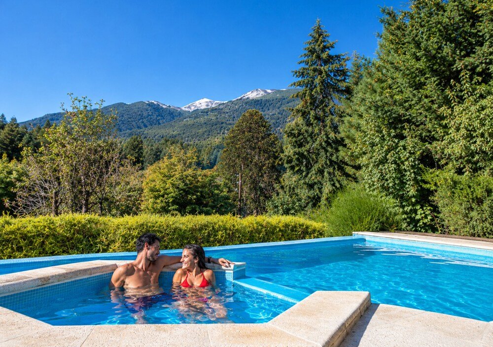 Swimming pool with a mountain view, surrounded by trees and a hedge