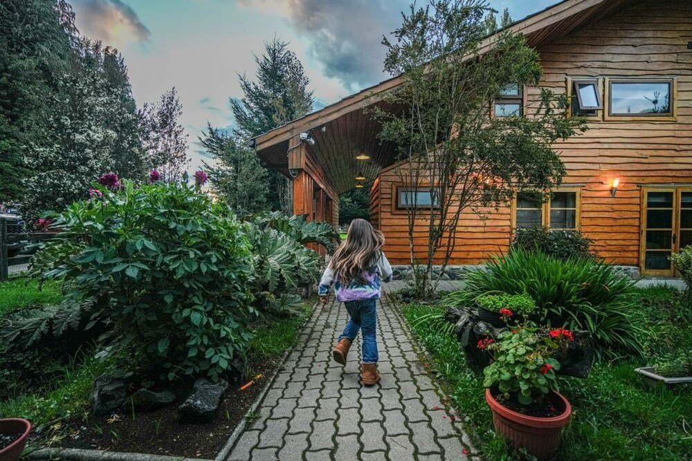 Cabaña de madera con galería cubierta rodeada de vegetación