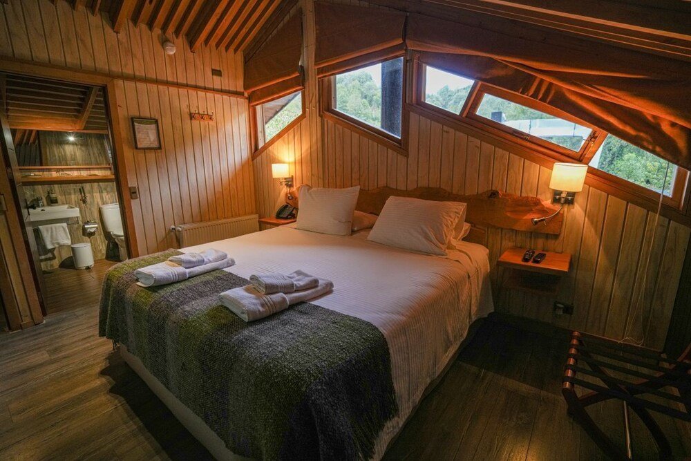Dormitorio de cabaña de madera con cama y dos lámparas de mesa de luz