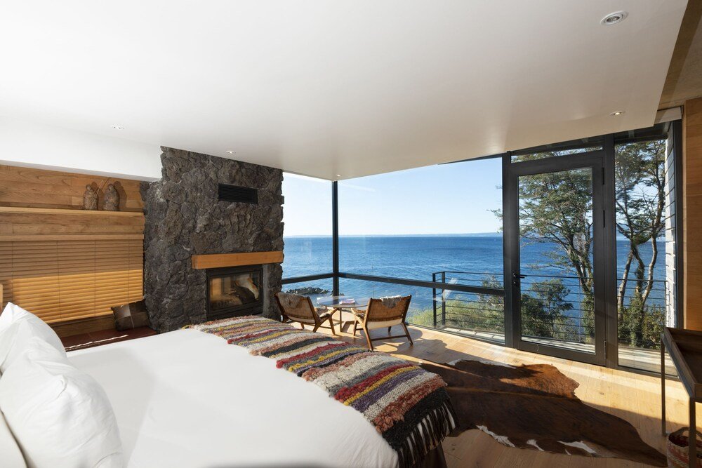 Bedroom with stone fireplace, sea view and balcony with chairs