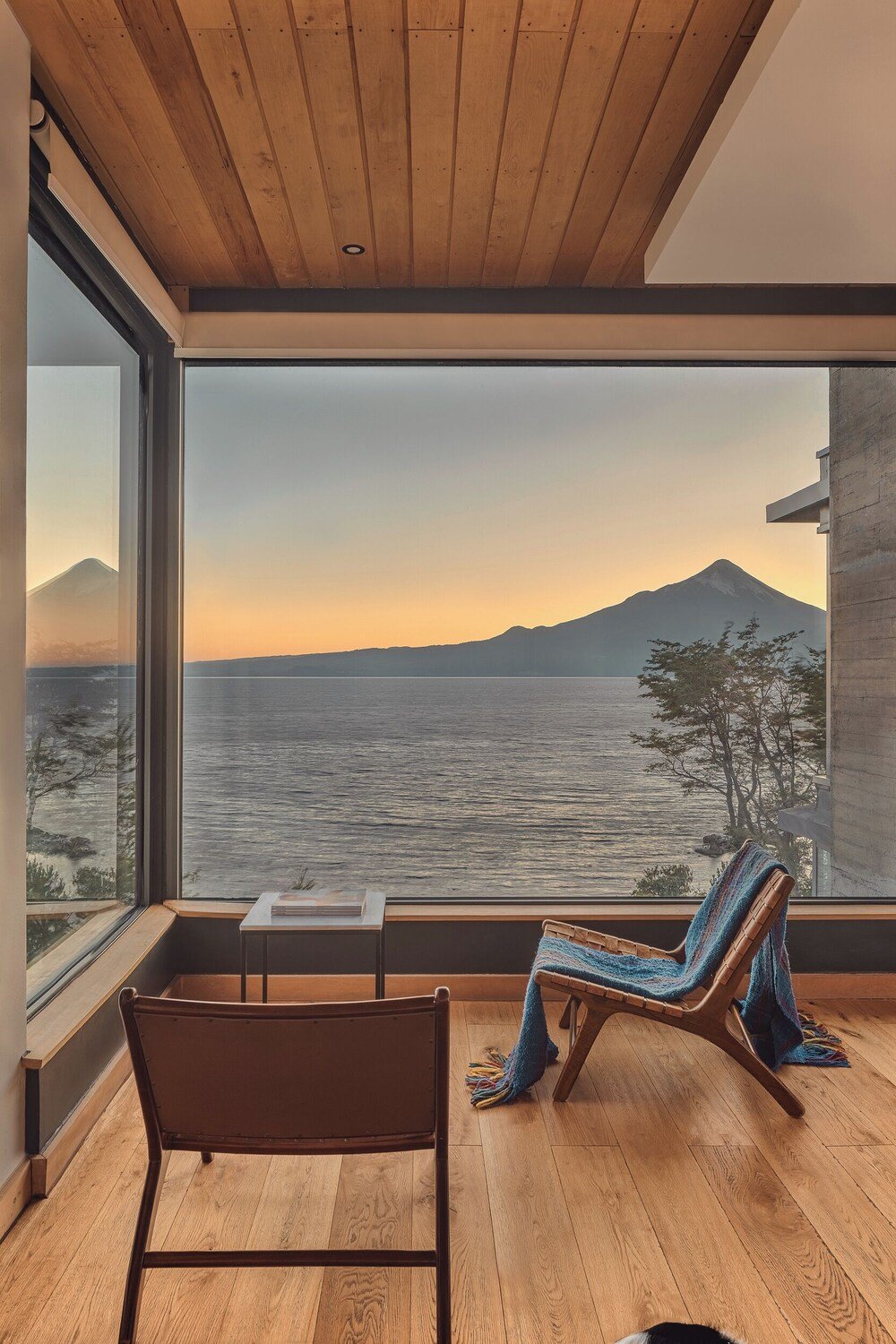 Room with large window over the water and mountain, bench and table
