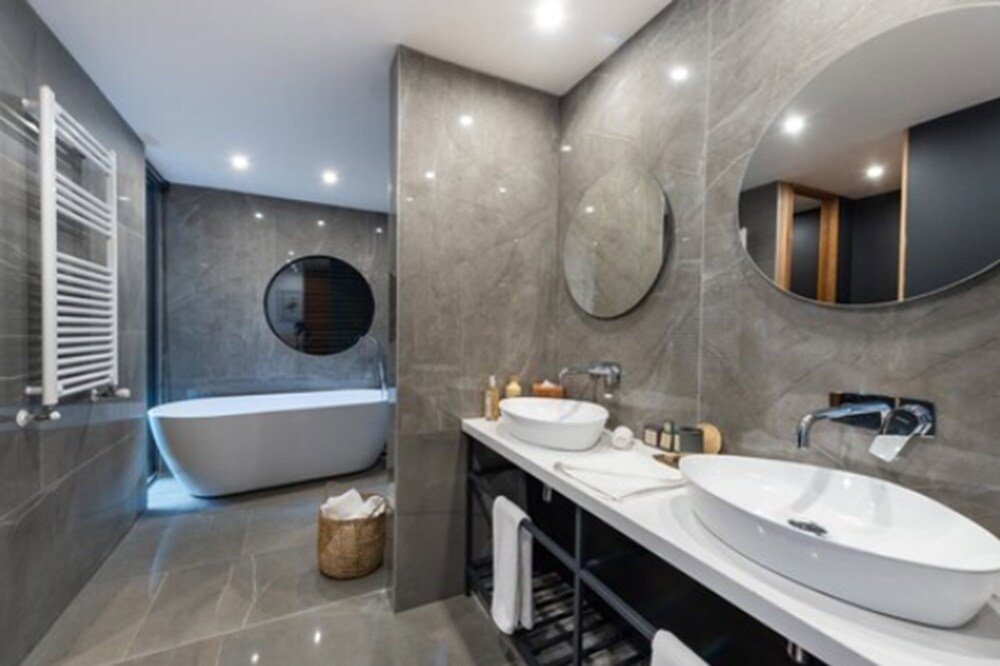 Modern bathroom with freestanding bathtub, two sinks and large mirror