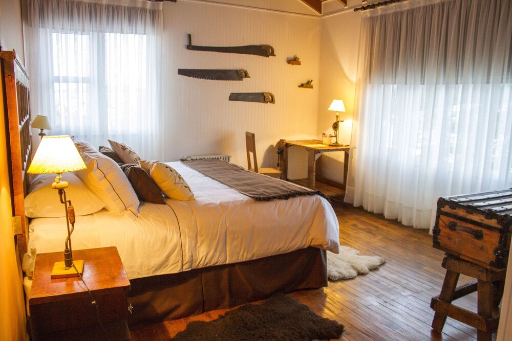 Dormitorio con cama, lámparas de mesa de luz y cómoda de madera