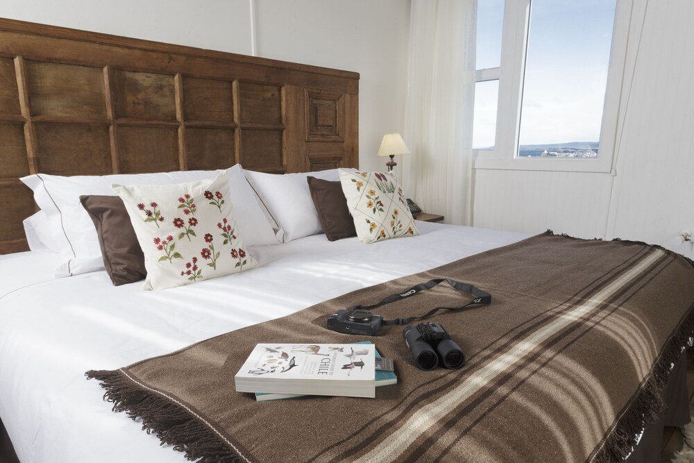Cama bien tendida con manta marrón y almohadones floreados