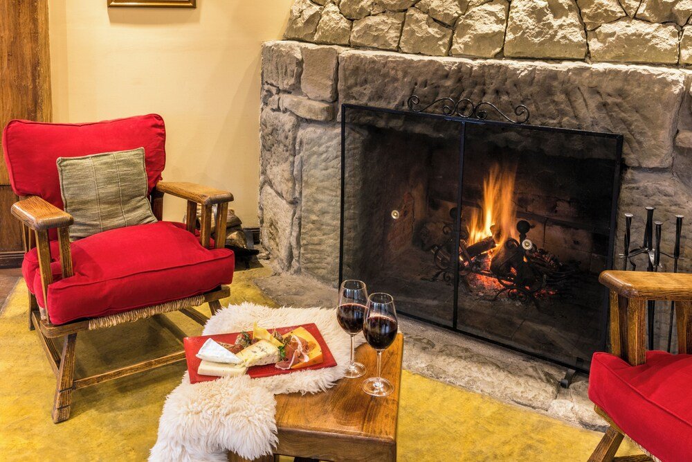 Habitación acogedora con chimenea y un sillón rojo