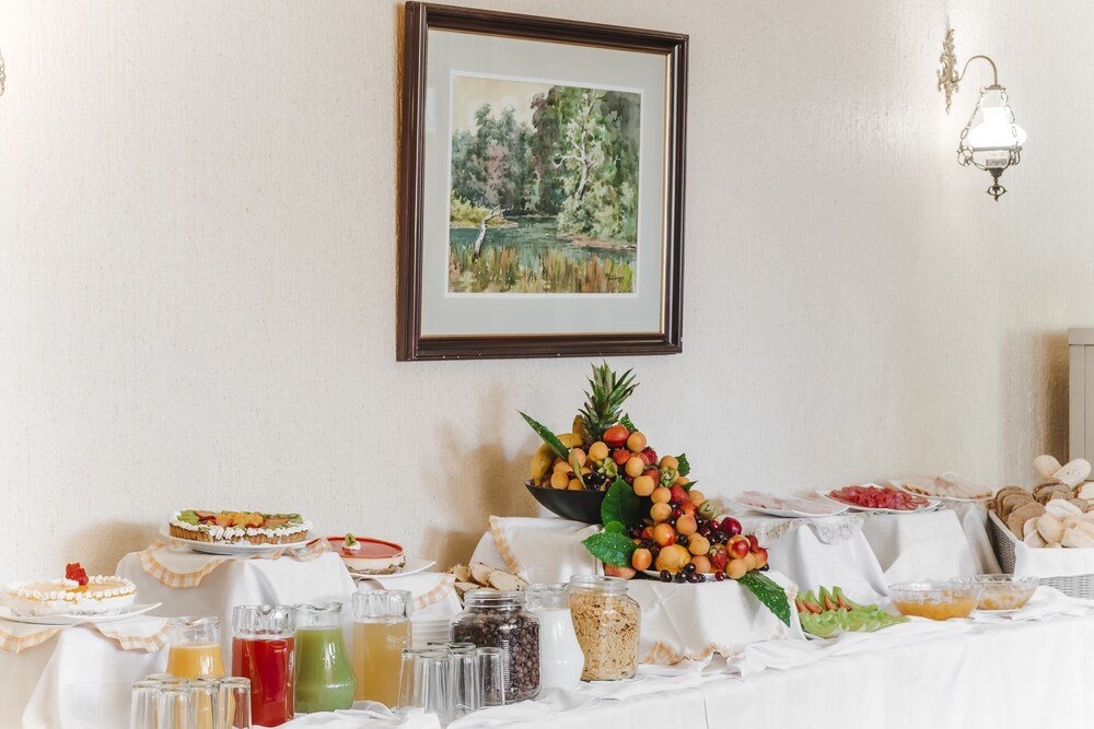 Buffet table with food and beverages and a landscape painting
