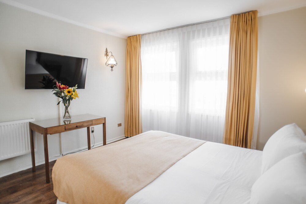 Hotel room with bed, wall-mounted TV and desk with flowers