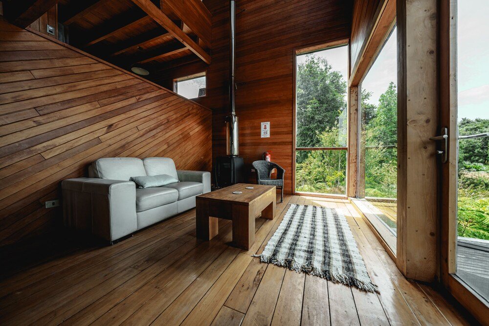 Wooden interior with sofa, table and view of greenery outside