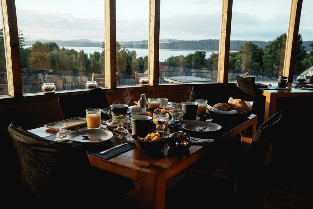 Breakfast table set with dishes overlooking a lake and forest
