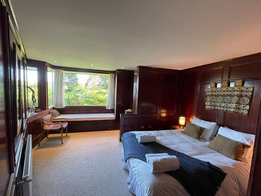 Bedroom with large bed, desk and window onto the greenery