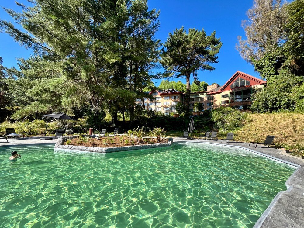 Clear pool surrounded by lounge chairs and forested area