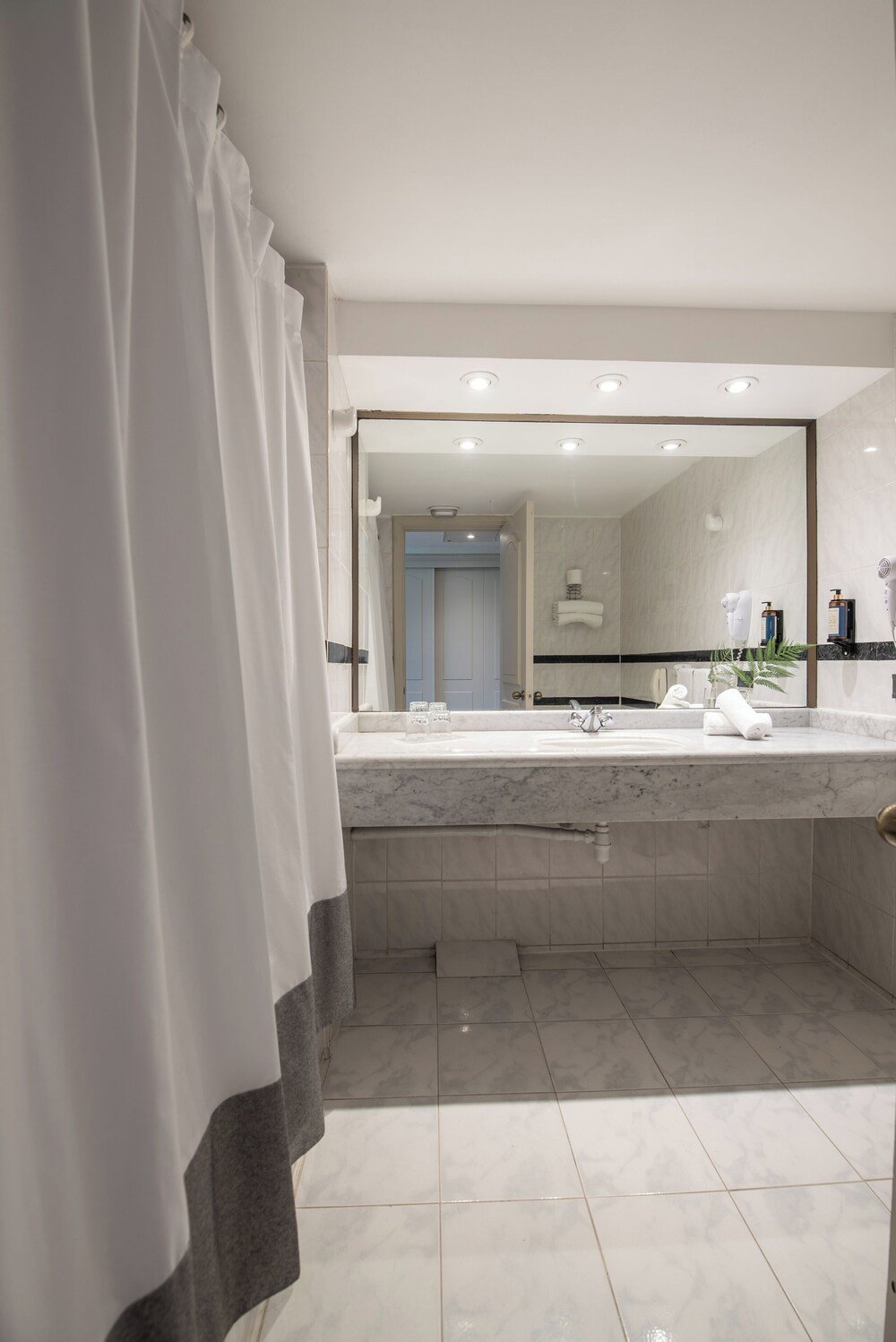 Modern bathroom with large mirror, marble sink and shower area