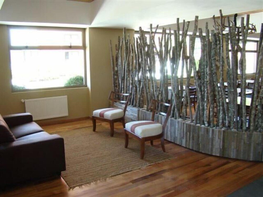 Living room with brown sofa, wooden chairs and woven rug