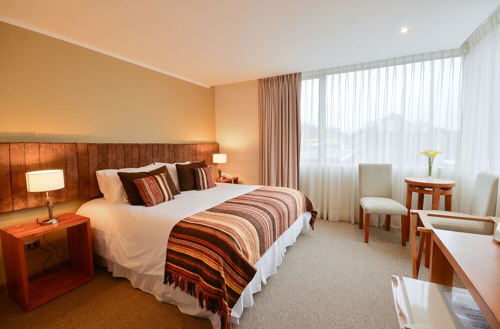 Hotel room with large bed, desk, chair and lamp